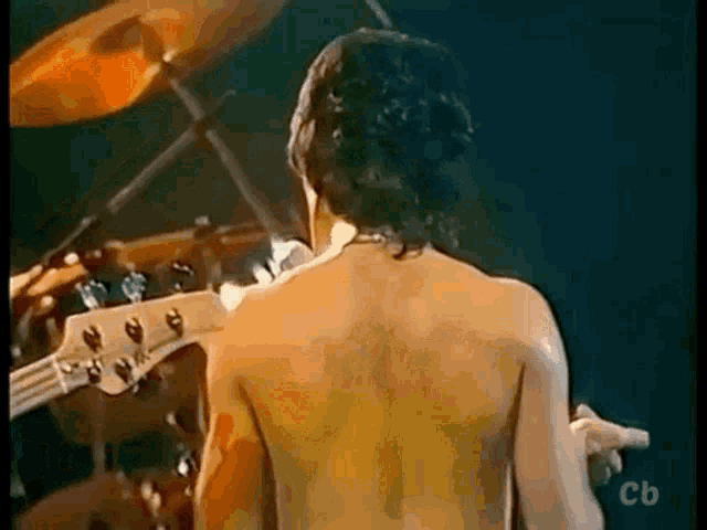 a man without a shirt is playing a bass guitar on a stage .