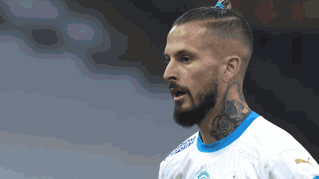 a man with a ponytail and a tattoo on his neck is wearing a puma shirt