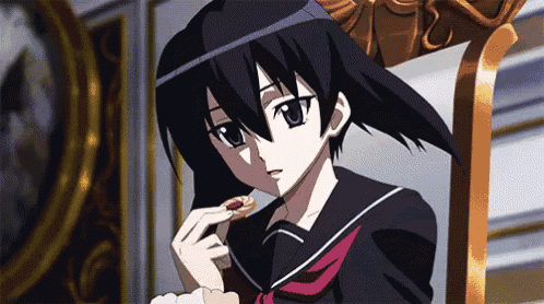 a girl in a school uniform is sitting on a chair eating a cookie