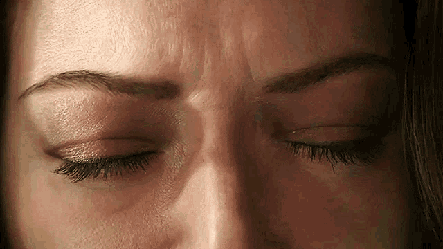 a close up of a woman 's face with her eyes closed and wrinkles on her forehead