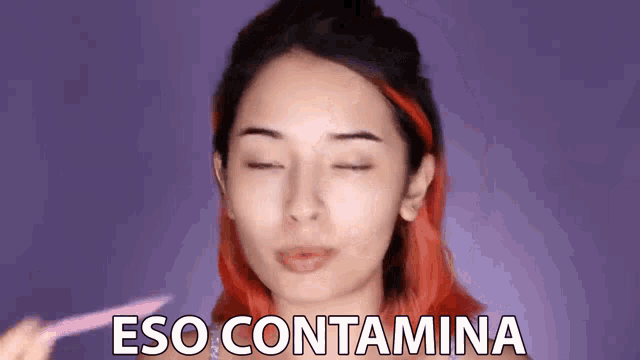 a woman with red hair is making a face with her eyes closed and the words eso contamina on the bottom of her face .