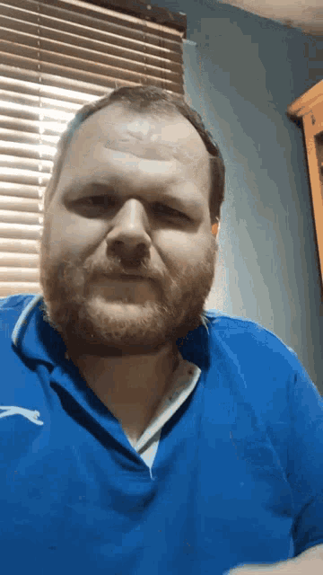 a man with a beard wearing a blue shirt with a puma logo