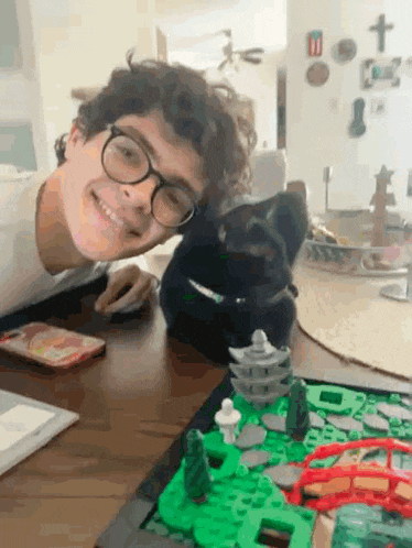 a young boy with glasses is sitting at a table with a cat .