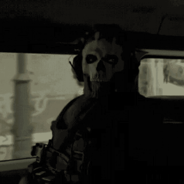 a man wearing a skull mask and headphones is sitting in the back seat of a car .