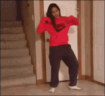 a woman in a red nike sweatshirt and black sweatpants is dancing in a room .
