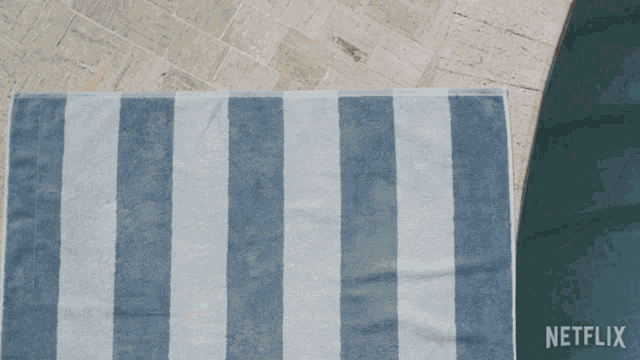a person laying on a blue and white striped towel with netflix written on the bottom