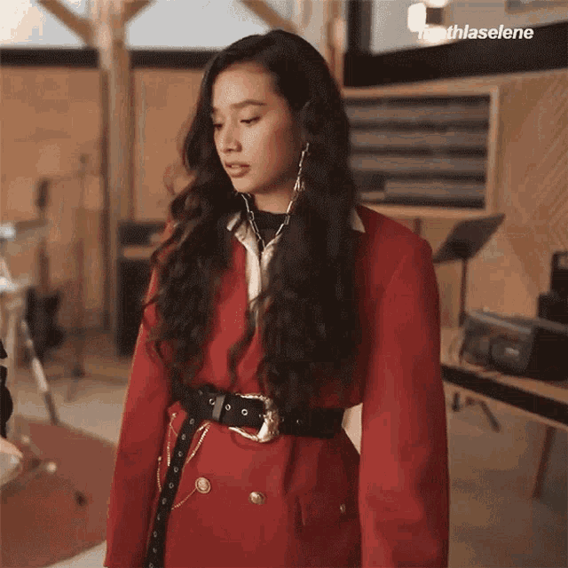 a woman is wearing a red jacket and a black belt