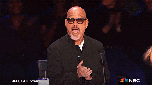 a bald man wearing glasses and a black jacket stands in front of a microphone with a nbc logo in the corner