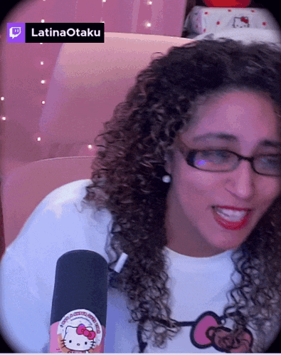 a woman with curly hair wearing glasses and a hello kitty sticker on a microphone