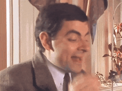 a man in a suit and tie is making a funny face with his eyes closed