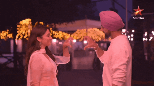 a man and a woman are making a heart shape with their hands in front of a star plus sign