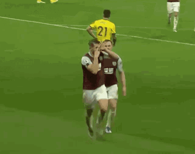 a couple of soccer players are hugging each other on a field .