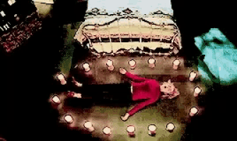 a woman in a red shirt is laying on the floor with candles around her