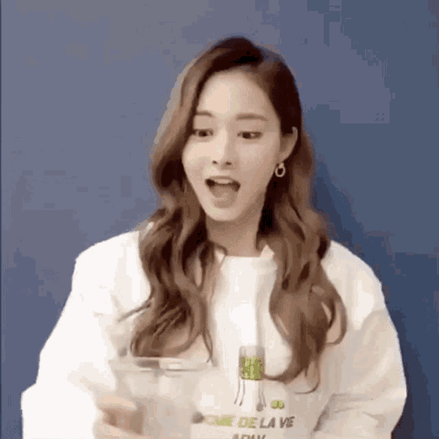a woman in a white sweatshirt is holding a glass of water .