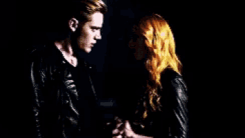 a man and a woman are standing next to each other in a dark room holding hands .