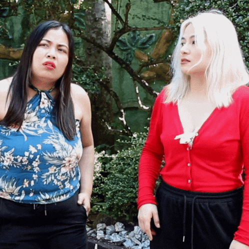 two women standing next to each other one in a red cardigan and the other in a blue top