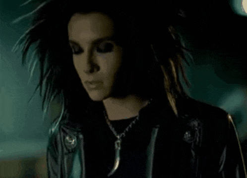 a woman with long hair is wearing a leather jacket and necklace .