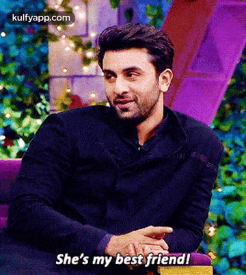 a man in a black jacket is sitting in a purple chair and says she 's my best friend .