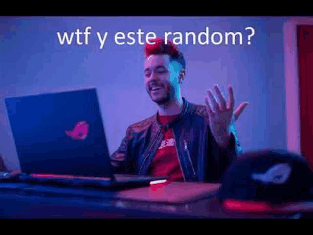 a man is sitting at a desk using a laptop computer and laughing .