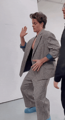 a man in a plaid suit is dancing with his hand in the air