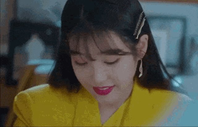a close up of a woman wearing a yellow suit and red lipstick .