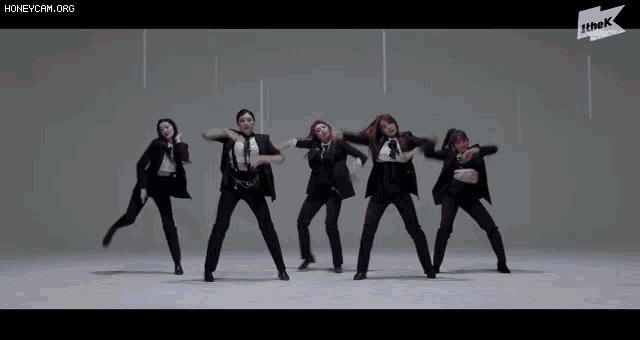 a group of women in suits and ties are dancing together