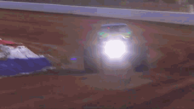 a monster truck is driving down a dirt road and its headlights are lit up
