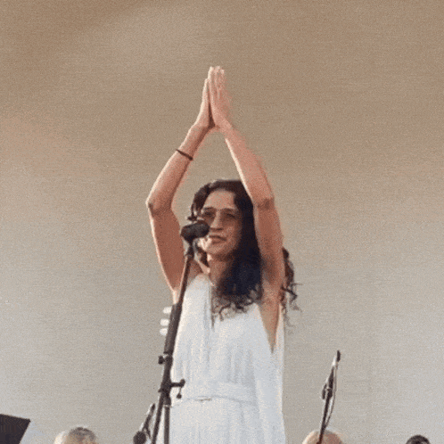 a woman in a white dress singing into a microphone