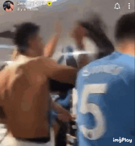 a shirtless man in a number 5 jersey is being held by another shirtless man