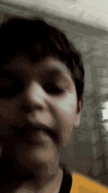 a close up of a young boy 's face with a yellow shirt on