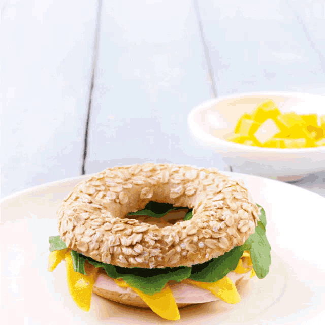 a bagel with ham cheese and spinach is on a plate with the word puray on the top