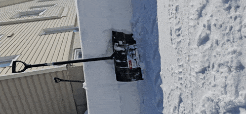 a snow shovel is sitting on top of a pile of snow near a building