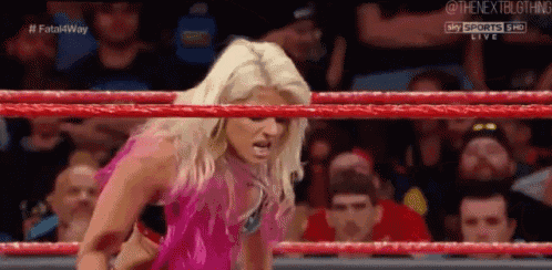 a woman in a pink top is standing in a wrestling ring .