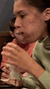 a woman is sitting at a table eating a sandwich with a spoon .