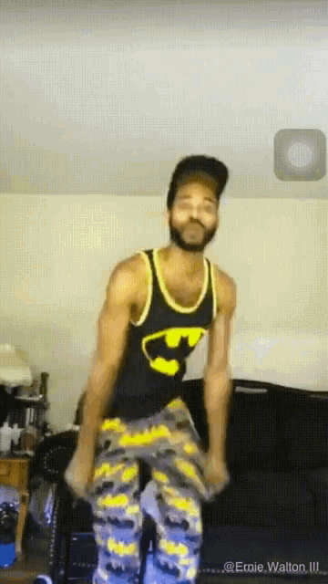 a man wearing a black tank top with a batman logo on it