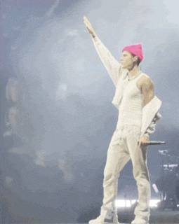 a man wearing a white tank top and a pink hat is holding a microphone