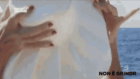 a woman is holding a white object in her hands in the ocean .