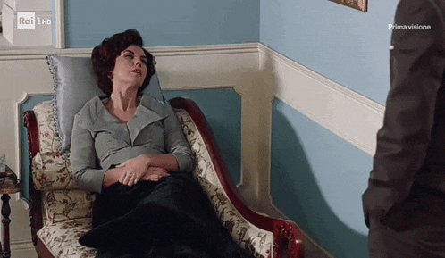 a woman sits in a chair in front of a sign that says " rai hd "