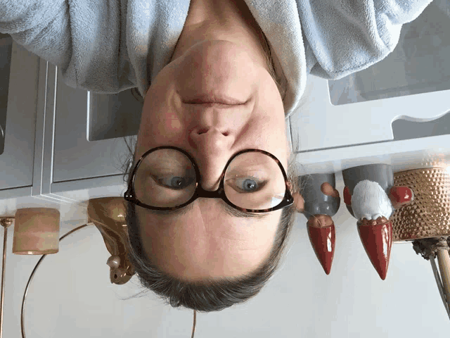 a woman wearing glasses is upside down in front of a shelf