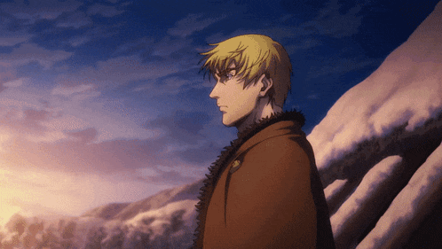a man with blonde hair is standing in front of a mountain