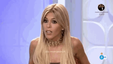 a woman with blonde hair and a choker looks at the camera in front of a sign that says 22:10