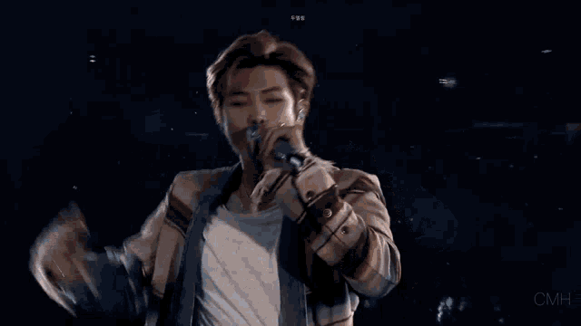 a man is holding a microphone in his hand and singing into it on a stage .