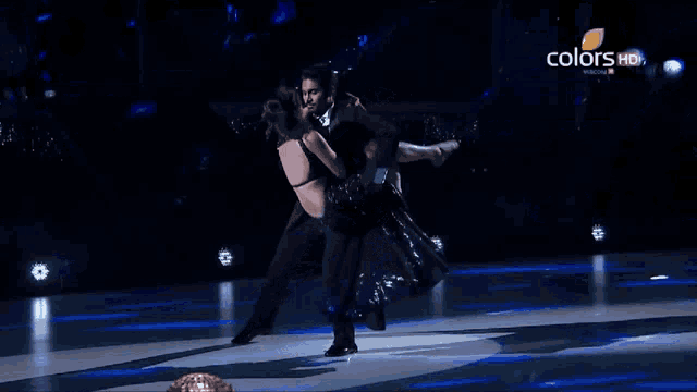 a man is holding a woman in his arms on a stage with the words colors hd behind him