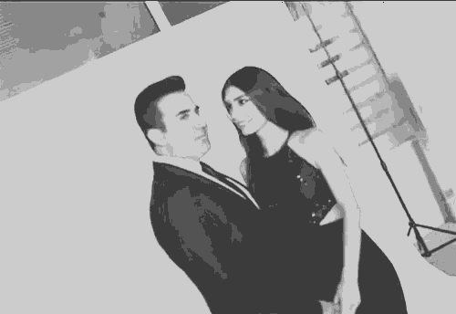 a man and a woman are standing next to each other in a black and white photo .