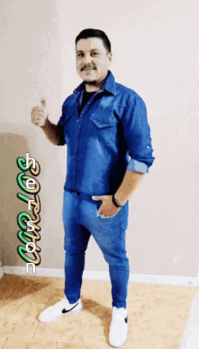 a man in a blue shirt is giving a thumbs up in front of a sign that says " software "