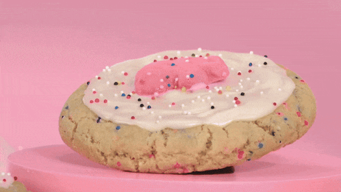 a cookie with pink frosting and sprinkles on a pink podium