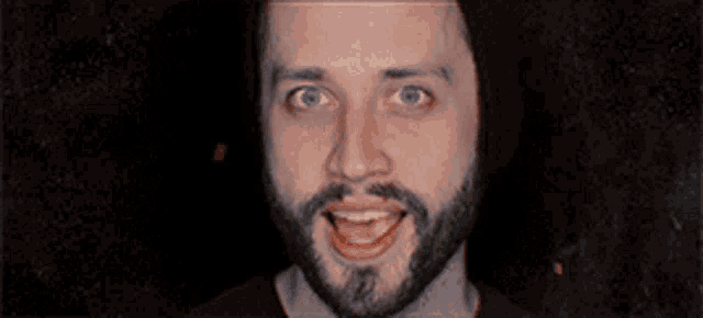 a man with a beard is making a funny face with his mouth open .