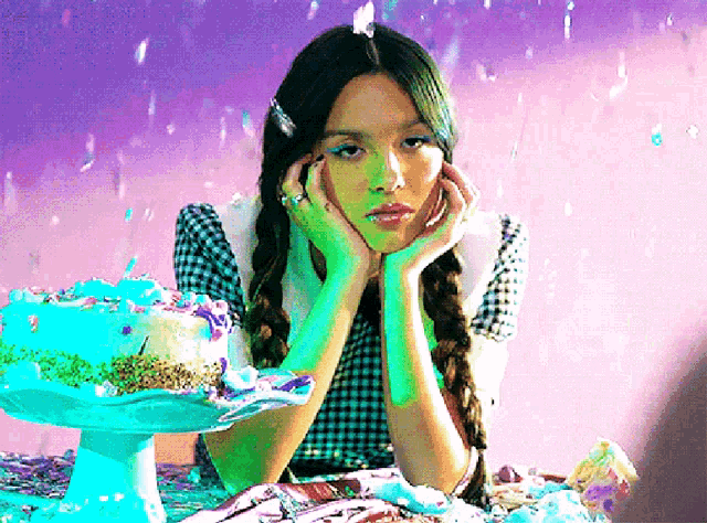 a girl is sitting at a table with a cake in front of her .
