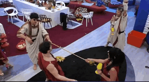 a group of people dressed in roman costumes are standing around a table .