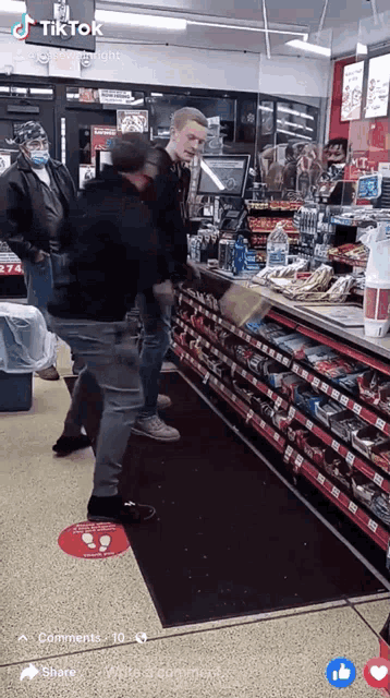 a man in a black jacket is standing in front of a store shelf